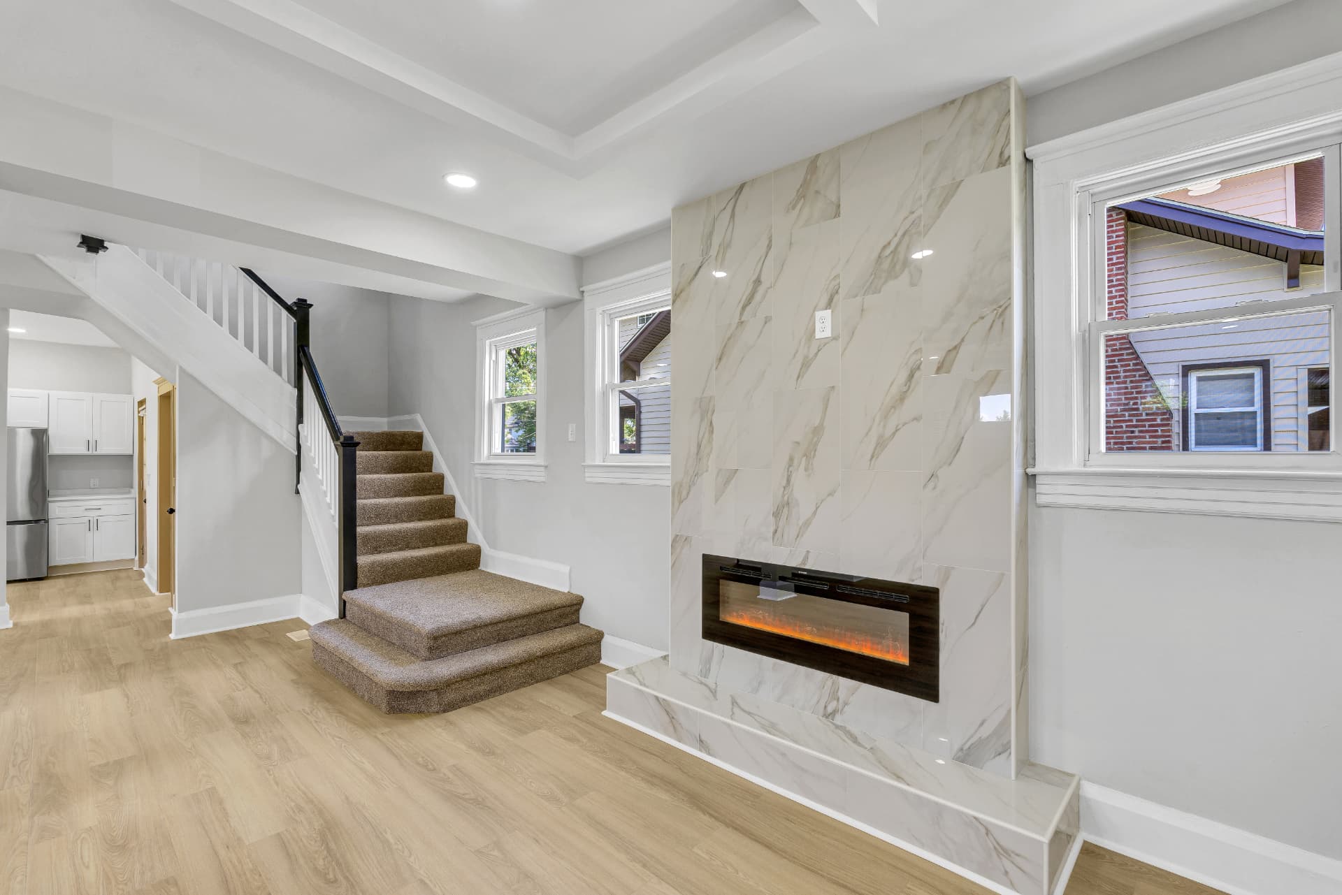 4016 Baltimore home — open living room with marble fireplace wall, staircase and light hardwood floors