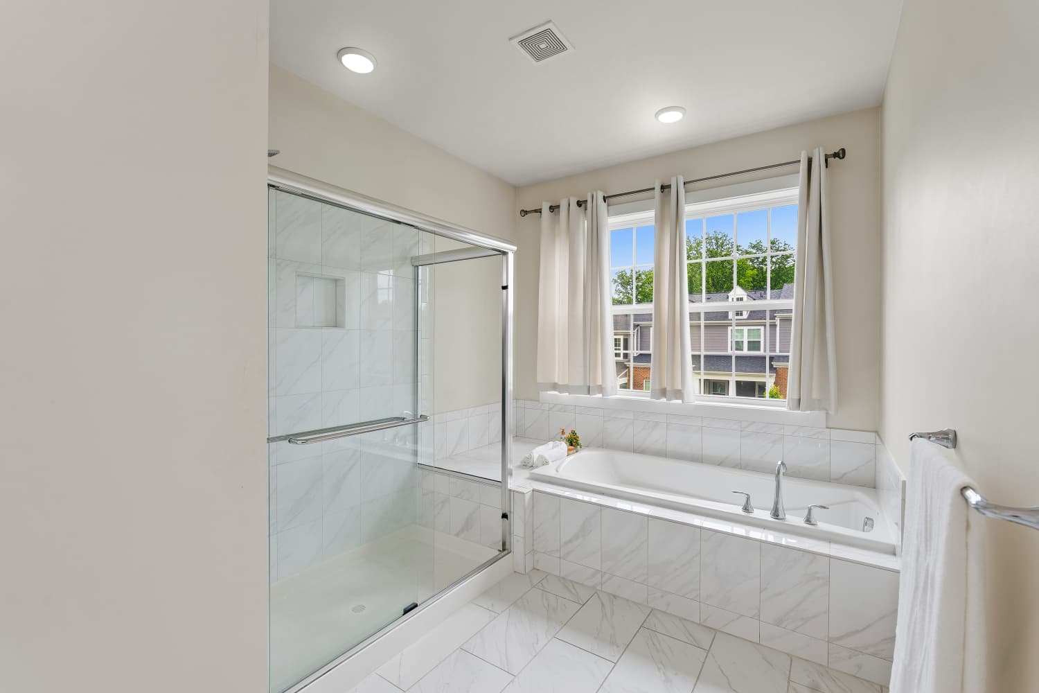 Marble tile bathroom with glass shower and soaking tub by the window