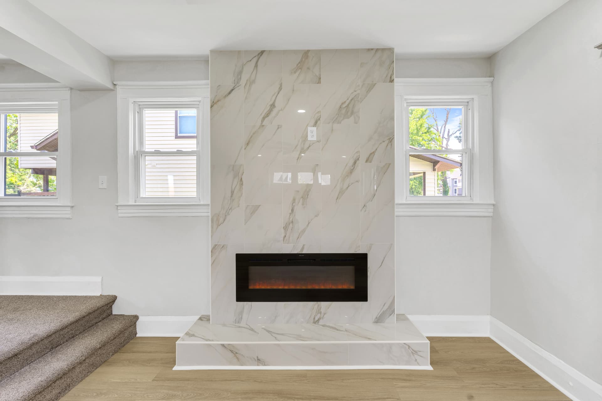 Vacant living room with marble-look fireplace before virtual staging