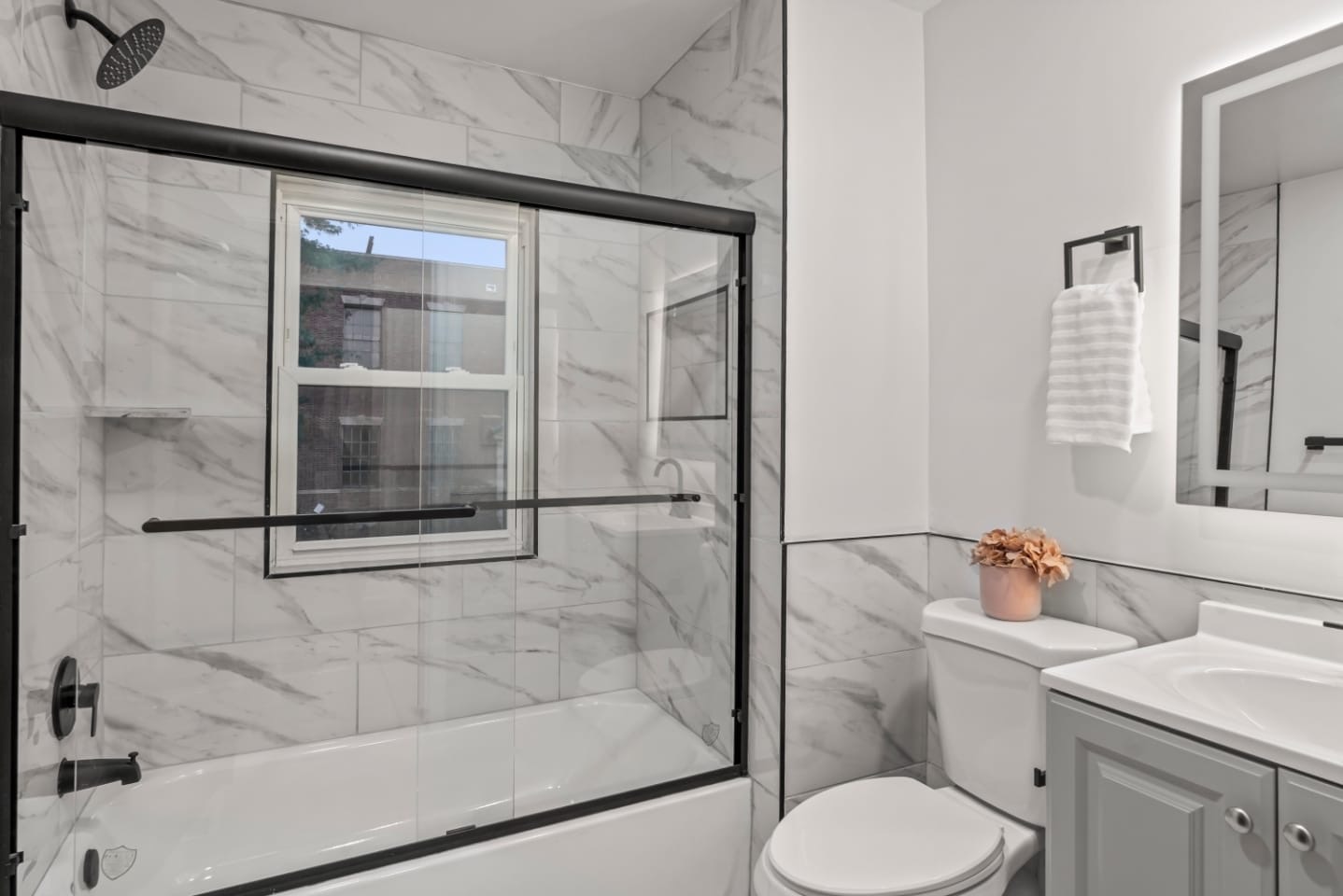 Renovated full bathroom with marble tile and matte black fixtures