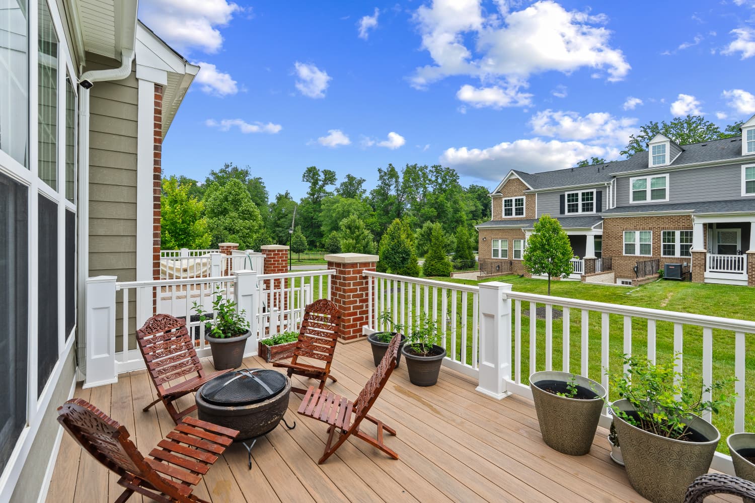 Composite deck with fire pit, seating and potted plants overlooking a green lawn