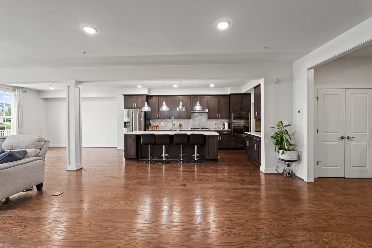 Great room opening to a dark-cabinet kitchen with hardwood floors