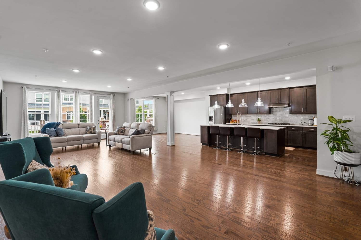 Open-concept living room and kitchen with teal accent chairs