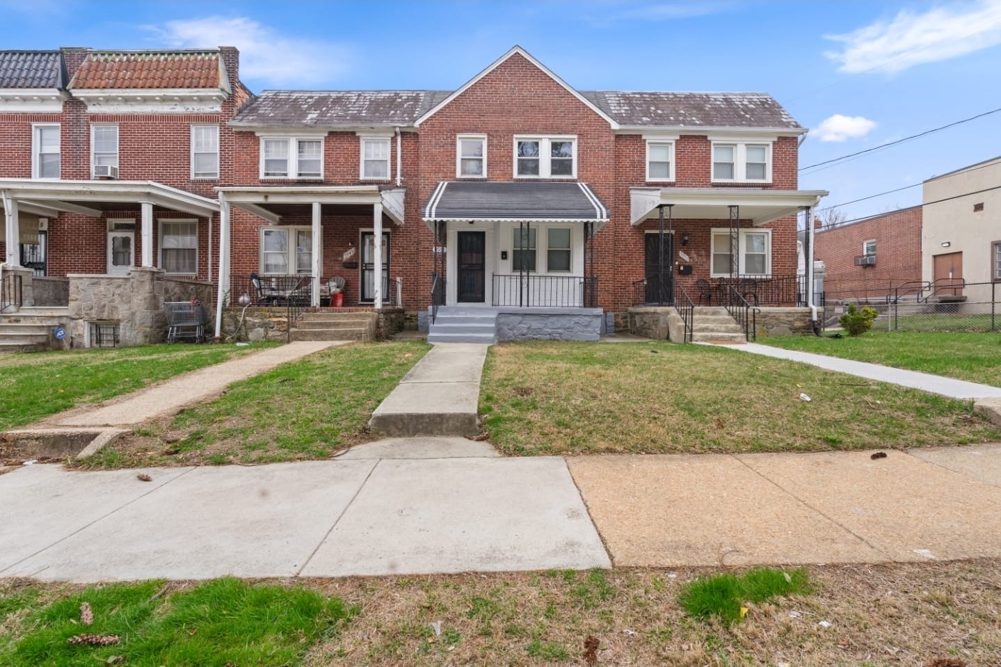Brick Baltimore rowhome front exterior with striped awning and porch