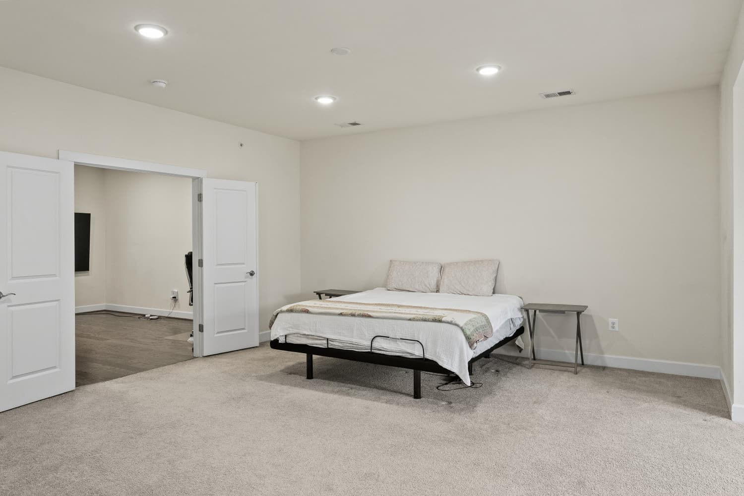 Spacious carpeted primary suite with double doors and recessed lighting