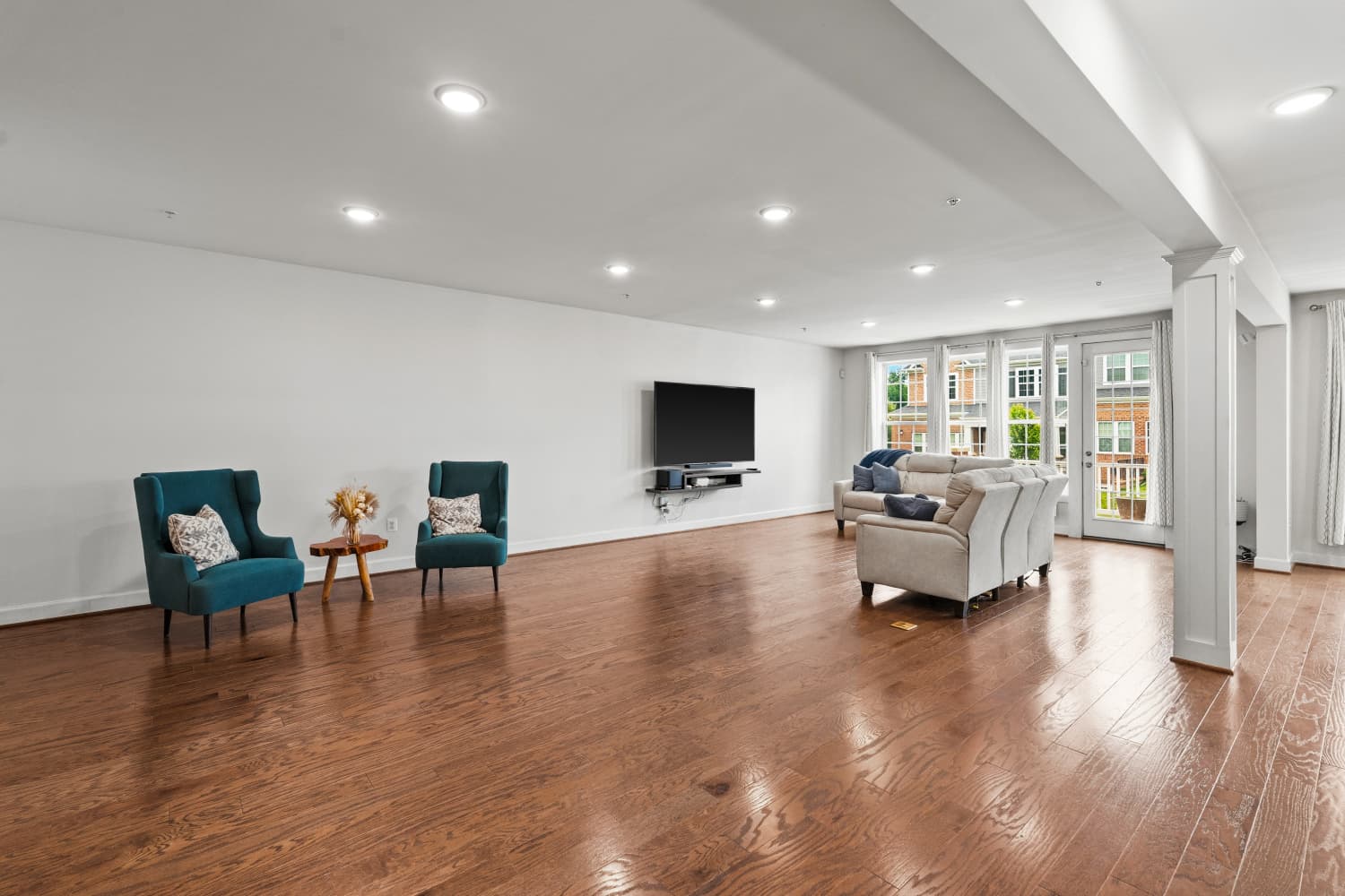 Spacious living room with natural light and teal wingback chairs