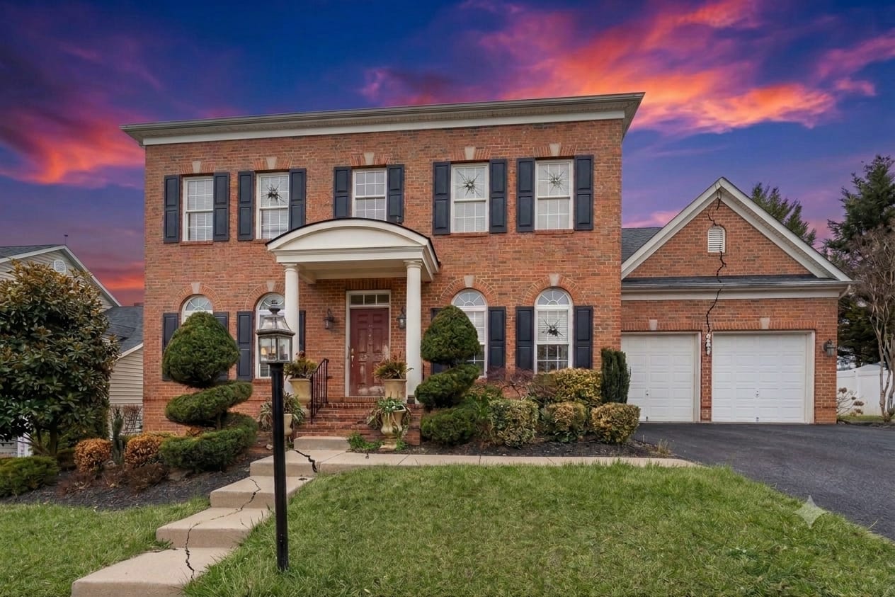 Brick colonial home photographed at twilight with a vivid sunset sky